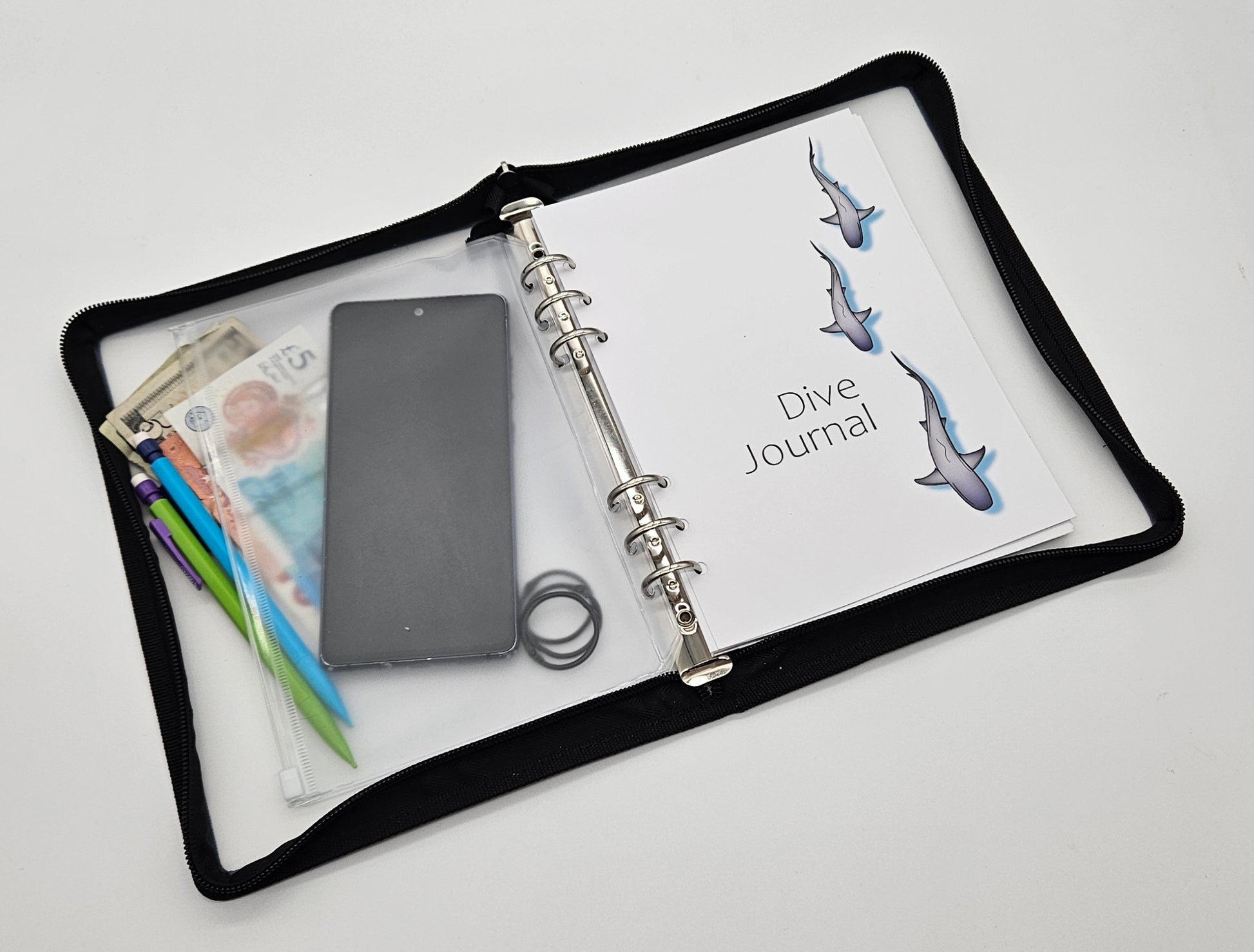 A5 size dive logbook with protective zip cover shown next to mobile phone for scale